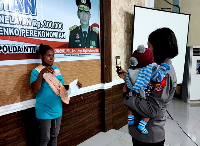 Gendong Bayi Sembari Foto, Polwan Ini Bantu Ibu Yang Kerepotan Saat Terima BTP