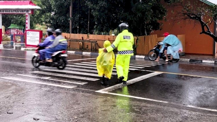 Basah Demi Keselamatan, Satlantas Polres Flotim Bantu Anak Menyeberang Meski Diguyur Hujan